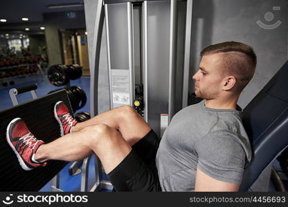 sport, fitness, bodybuilding, lifestyle and people concept - man exercising and flexing leg muscles on gym machine