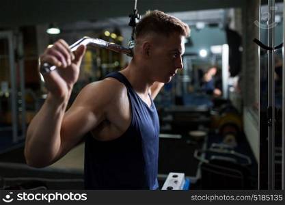 sport, fitness, bodybuilding, lifestyle and people concept - man exercising and flexing muscles on lat pull-down cable machine in gym. man flexing muscles on cable machine in gym
