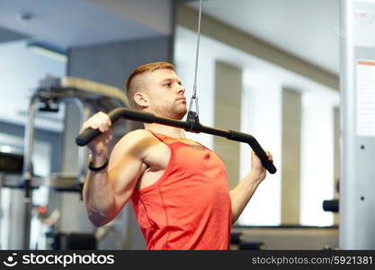 sport, fitness, bodybuilding, lifestyle and people concept - man exercising and flexing muscles on cable machine in gym