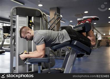 sport, fitness, bodybuilding, lifestyle and people concept - man exercising and flexing muscles on leg curl machine in gym