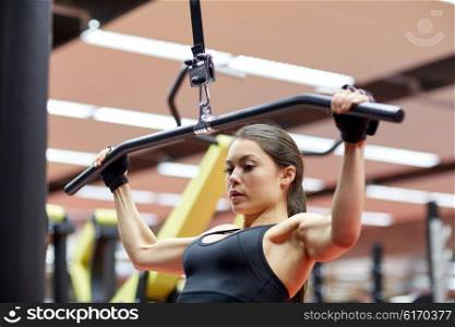 sport, fitness, bodybuilding, lifestyle and people concept - woman flexing arm muscles on cable machine in gym