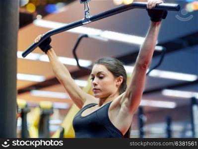sport, fitness, bodybuilding, lifestyle and people concept - woman flexing arm muscles on cable machine in gym. woman flexing arm muscles on cable machine in gym