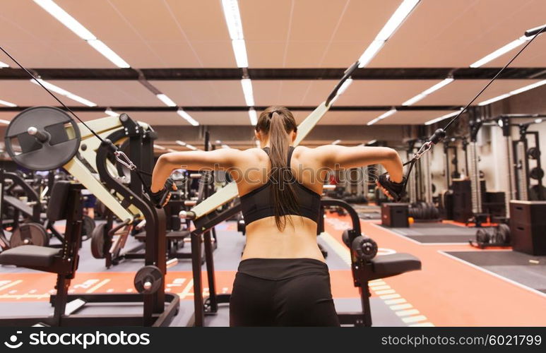 sport, fitness, bodybuilding, lifestyle and people concept - woman flexing muscles on cable machine in gym