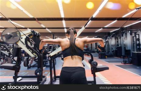 sport, fitness, bodybuilding, lifestyle and people concept - woman flexing muscles on cable machine in gym. woman flexing muscles on cable machine in gym