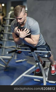 sport, fitness, bodybuilding, lifestyle and people concept - young man flexing back and abdominal muscles on bench in gym