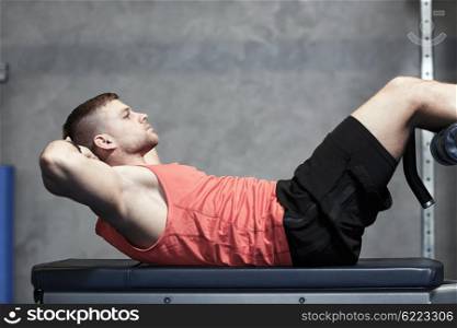 sport, fitness, bodybuilding, lifestyle and people concept - young man making abdominal exercises in gym
