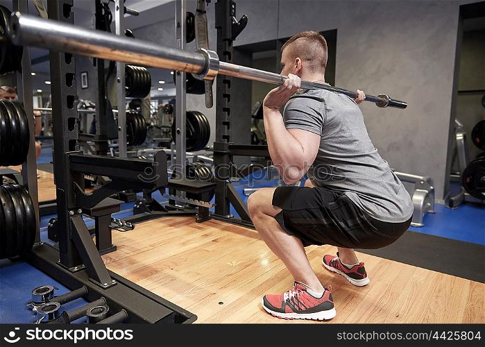 sport, fitness, bodybuilding, lifestyle and people concept - young man with bar of barbell flexing muscles in gym