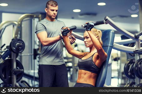 sport, fitness, bodybuilding, teamwork and people concept - young woman and personal trainer flexing muscles on gym machine