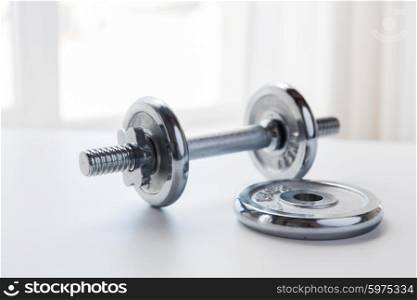 sport, fitness, bodybuilding, weightlifting and objects concept - close up of iron dumbbell on table