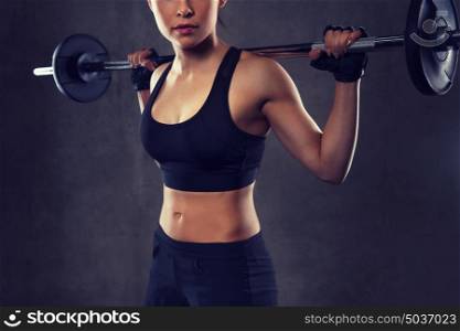 sport, fitness, bodybuilding, weightlifting and people concept - close up of young woman with barbell flexing muscles in gym. young woman flexing muscles with barbell in gym