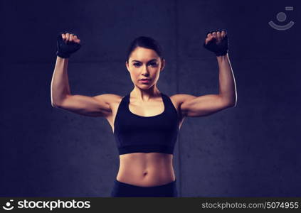 sport, fitness, bodybuilding, weightlifting and people concept - young woman flexing muscles in gym. young woman flexing muscles in gym