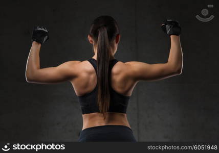 sport, fitness, bodybuilding, weightlifting and people concept - young woman flexing muscles in gym