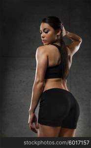 sport, fitness, bodybuilding, weightlifting and people concept - young woman posing and showing buttocks in gym