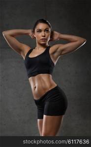 sport, fitness, bodybuilding, weightlifting and people concept - young woman posing and showing muscles in gym
