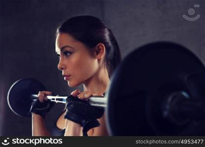 sport, fitness, bodybuilding, weightlifting and people concept - young woman with barbell flexing muscles in gym. young woman flexing muscles with barbell in gym