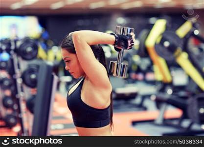 sport, fitness, bodybuilding, weightlifting and people concept - young woman with dumbbell flexing muscles in gym from back. young woman flexing muscles with dumbbell in gym