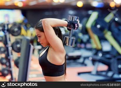 sport, fitness, bodybuilding, weightlifting and people concept - young woman with dumbbell flexing muscles in gym from back. young woman flexing muscles with dumbbell in gym