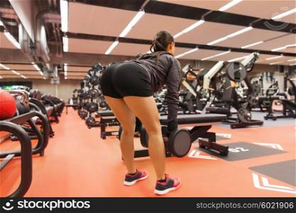sport, fitness, bodybuilding, weightlifting and people concept - young woman with dumbbells flexing muscles in gym from back