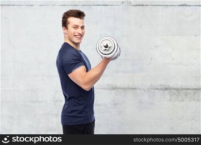 sport, fitness, exercising, bodybuilding and people concept - happy smiling sportive young man with dumbbell flexing muscles over concrete wall background. happy sportive young man with dumbbell