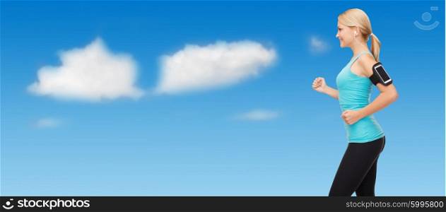 sport, fitness, exercising, technology and people - sporty woman running and listening to music from smartphone over blue sky and clouds background