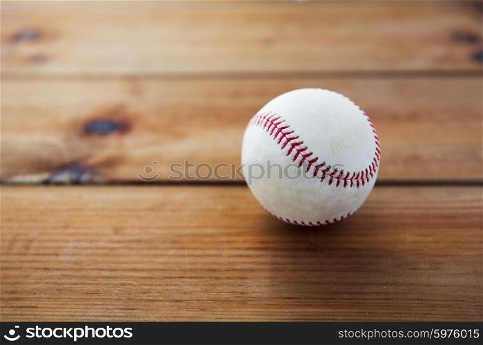 sport, fitness, game and objects concept - close up of baseball ball on wooden floor