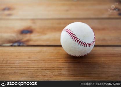 sport, fitness, game and objects concept - close up of baseball ball on wooden floor