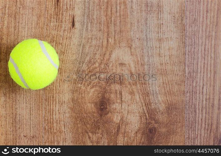 sport, fitness, game, sports equipment and objects concept - close up of tennis ball on wooden floor from top
