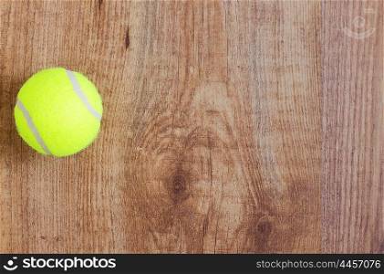 sport, fitness, game, sports equipment and objects concept - close up of tennis ball on wooden floor from top