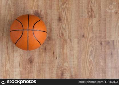 sport, fitness, game, sports equipment and objects concept - close up of basketball ball on wooden floor from top