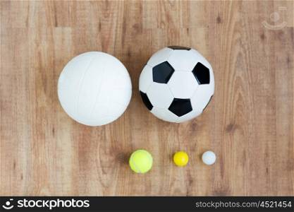 sport, fitness, game, sports equipment and objects concept - close up of different sports balls set on wooden floor from top