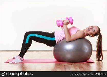 Sport, fitness, gym, people concept. Beautiful girl with pink dumbbells. Lady is lying on the fit ball.. Beautiful girl with pink dumbbells.