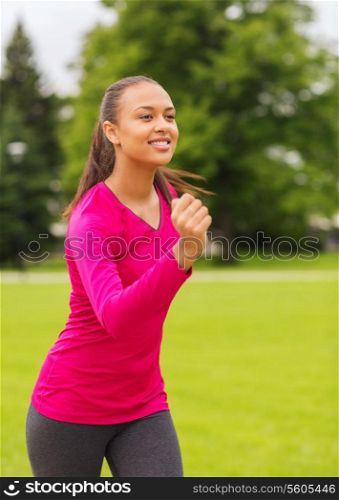 sport, fitness, health and people concept - smiling young african american woman running outdoors