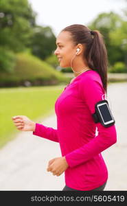 sport, fitness, health, technology and people concept - smiling young african american woman running with smartphone and earphones outdoors