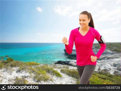 sport, fitness, health, technology and people concept - smiling young african american woman with smartphone and earphones running on beach and listening to music