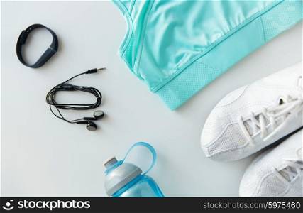sport, fitness, healthy lifestyle and objects concept - close up of female sports clothing, heart-rate watch, earphones and bottle set