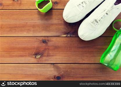 sport, fitness, healthy lifestyle and objects concept - close up of sneakers, bracelet and water bottle on wooden floor. close up of sneakers, bracelet and water bottle