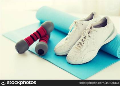 sport, fitness, healthy lifestyle and objects concept - close up of sneakers, dumbbells and sports mat. close up of sneakers, dumbbells and sports mat