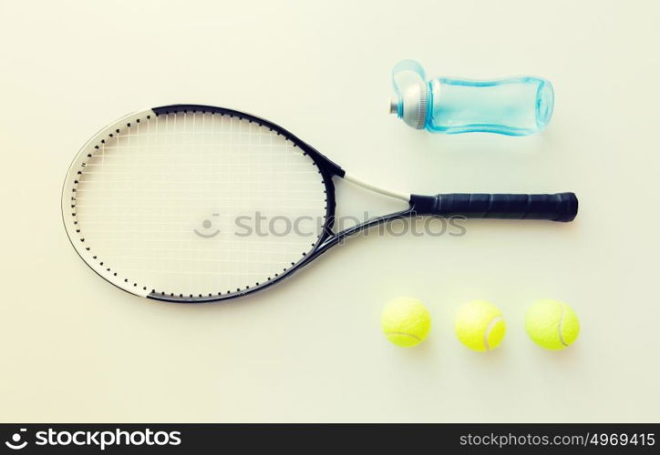 sport, fitness, healthy lifestyle and objects concept - close up of tennis racket with balls and bottle. close up of tennis racket with balls and bottle