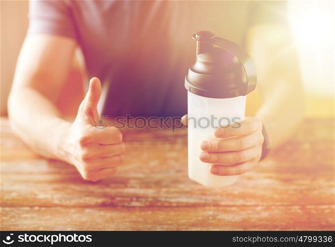 sport, fitness, healthy lifestyle and people concept - close up of man in fitness bracelet with protein shake bottle showing thumbs up