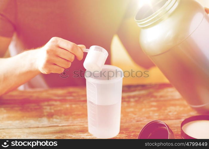 sport, fitness, healthy lifestyle and people concept - close up of man with jar and bottle preparing protein shake