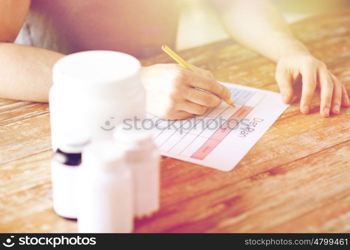 sport, fitness, healthy lifestyle and people concept - close up of man with protein jars writing diet plan at home