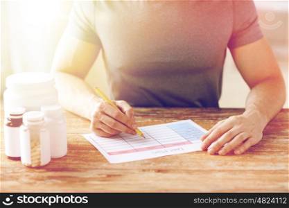 sport, fitness, healthy lifestyle and people concept - close up of man with protein jars writing diet plan at home