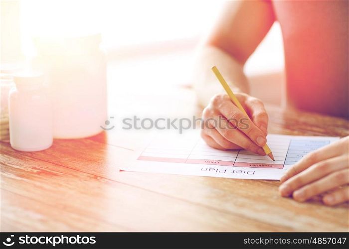 sport, fitness, healthy lifestyle and people concept - close up of man with protein jars writing diet plan at home