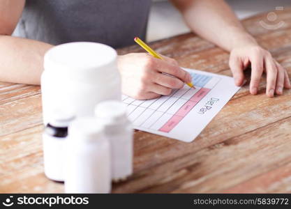 sport, fitness, healthy lifestyle and people concept - close up of man with protein jars writing diet plan at home