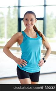 sport, fitness, healthy lifestyle and people concept - happy smiling young sporty woman posing in gym