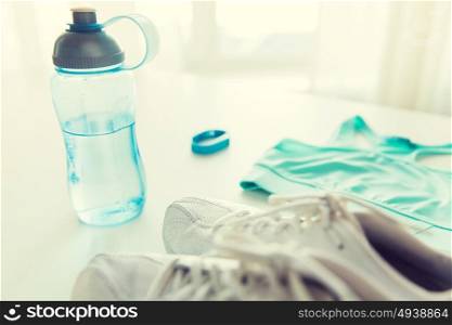 sport, fitness, healthy lifestyle, cardio training and objects concept - close up of female sports clothing, heart-rate watch and bottle set. close up of sportswear, bracelet and bottle