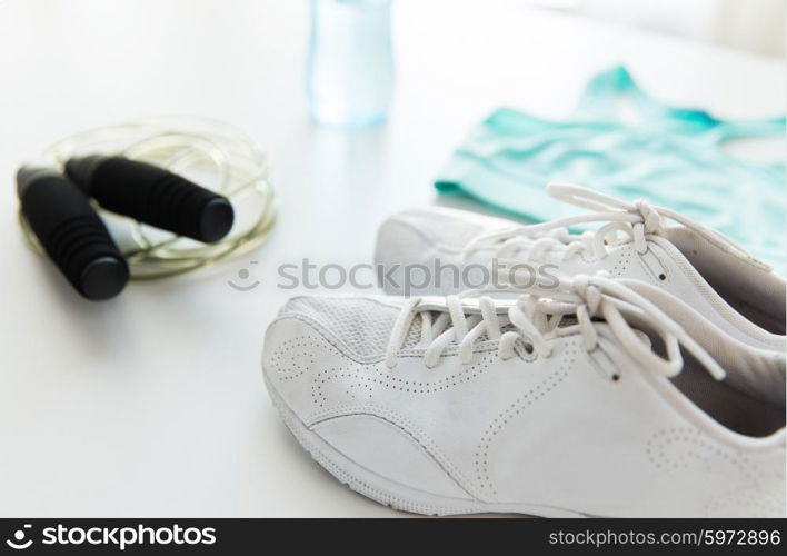 sport, fitness, healthy lifestyle, cardio training and objects concept - close up of female sports clothing, skipping rope and bottle set