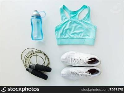 sport, fitness, healthy lifestyle, cardio training and objects concept - close up of female sports clothing, skipping rope and bottle set