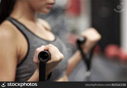 sport, fitness, lifestyle and people concept - close up of young woman flexing muscles on cable gym machine