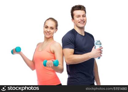 sport, fitness, lifestyle and people concept - happy sportive man and woman with dumbbell and water bottle. sportive man and woman with dumbbell and water